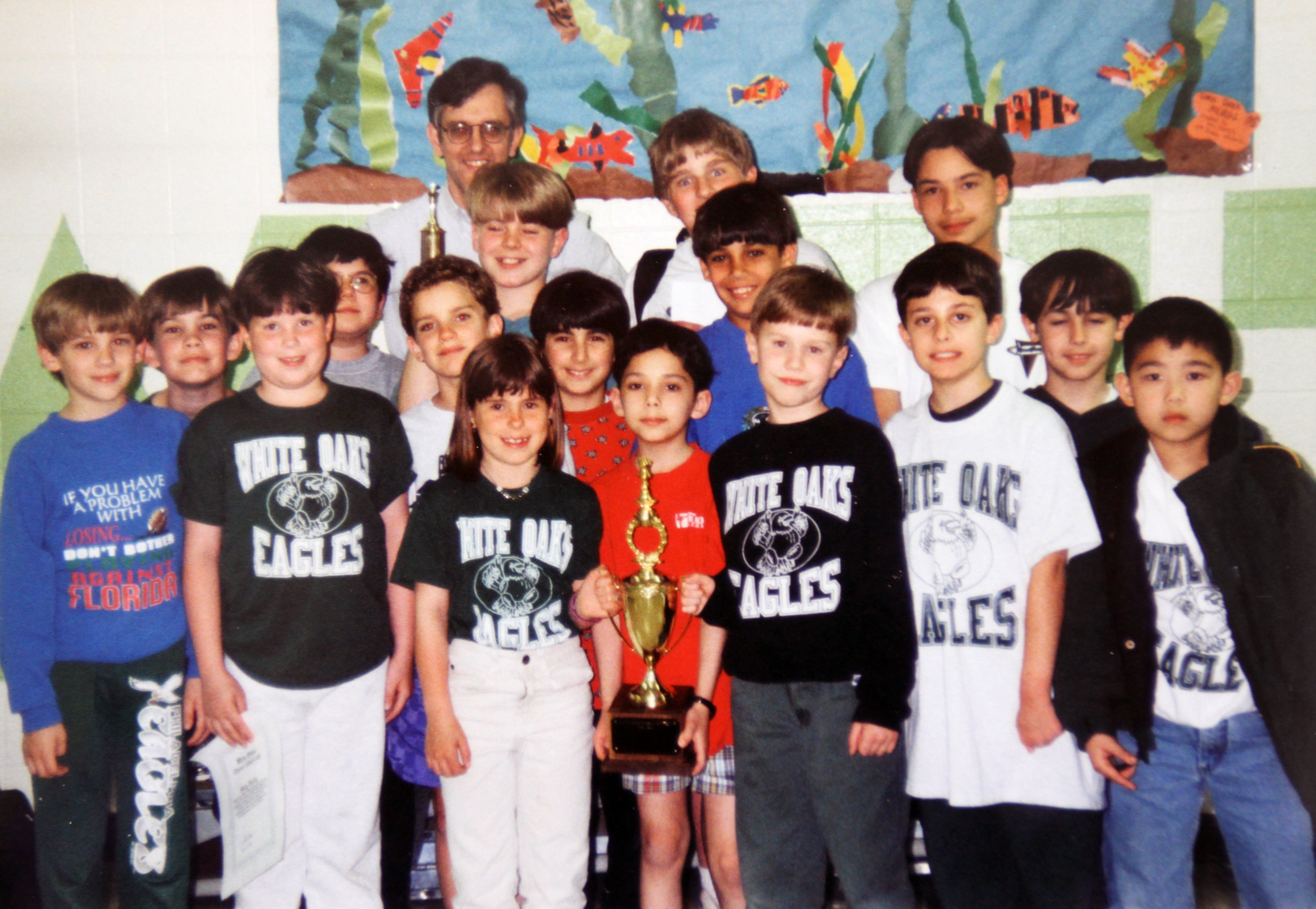 Photograph of the championship-winning chess team posing with their trophy.